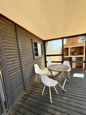 a patio with a table and chairs on a deck at Kings 93 Cabins in Tierpoort