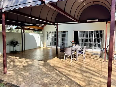 a patio with a table and chairs under an umbrella at Escape At House 68 in Pretoria
