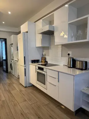 a kitchen with white appliances and a wooden floor at Acoustic Apartment in Pretoria