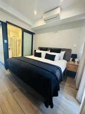 a bedroom with a large bed with a black blanket at Acoustic Apartment in Pretoria