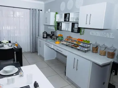 a kitchen with white cabinets and a counter with food on it at Relmies Place in Modimolle