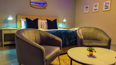 a hotel room with a bed and two chairs and a table at Mercy Boutique Hotel in Thohoyandou