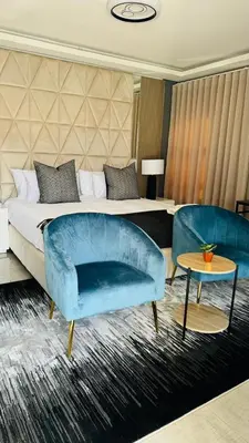 a bedroom with a bed and a blue couch and tables at Mercy Boutique Hotel in Thohoyandou