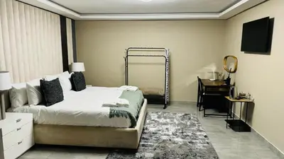 a bedroom with a bed and a mirror and a desk at Mercy Boutique Hotel in Thohoyandou
