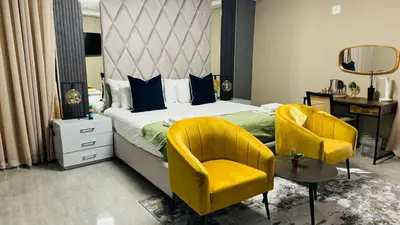 a bedroom with a bed and two yellow chairs at Mercy Boutique Hotel in Thohoyandou