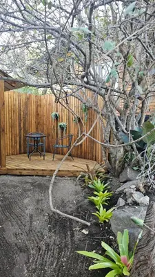 a wooden deck with a table next to a fence at Marepe Flora Bell mimosa in Kampersrus AH