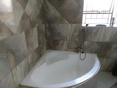 a white bath tub in a bathroom with a window at Thiwani Guest House in Tembisa