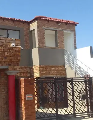 a brick house with a metal gate and stairs at Thiwani Guest House in Tembisa