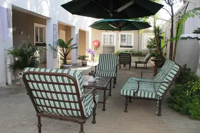 a patio with chairs and a table with an umbrella at Firwood Lodge in Pretoria