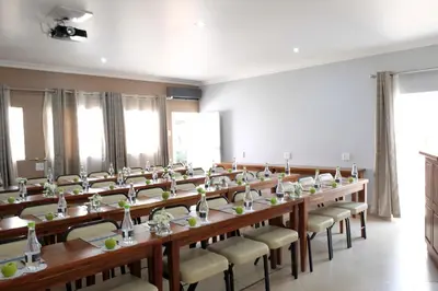 a large room with long tables and chairs at Firwood Lodge in Pretoria