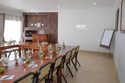 a conference room with a long wooden table and chairs at Firwood Lodge in Pretoria