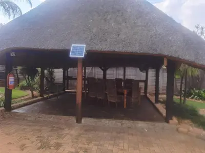 a gazebo with a thatched roof with a table at Bosveld Kuier Woonstel in Bela-Bela