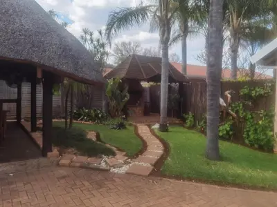 a garden with palm trees and a house at Bosveld Kuier Woonstel in Bela-Bela