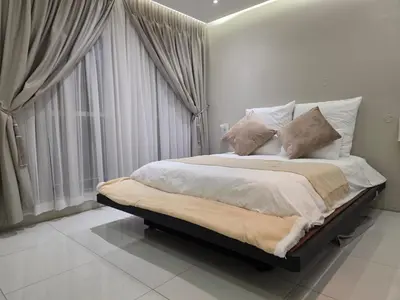 a white bedroom with a large bed with pillows at Hatfield on Park A in Pretoria
