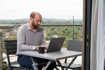 a man sitting at a table with a laptop at When Away - Your Home Away from Home in Pretoria