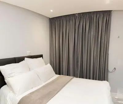 a bed with white pillows in front of a window at Hatfield on Park B in Pretoria