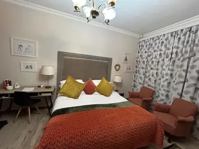 a bedroom with a bed and a desk and a chair at Galaxy Retreat in Pretoria