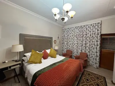 a bedroom with a bed and a desk and a chandelier at Galaxy Retreat in Pretoria