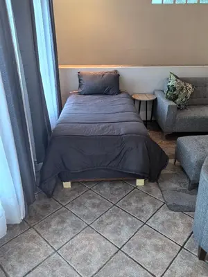 a bed sitting in a room next to a couch at Pearlman Loft in Tzaneen