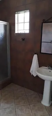 a bathroom with a sink and a toilet and a window at Pearlman Loft in Tzaneen