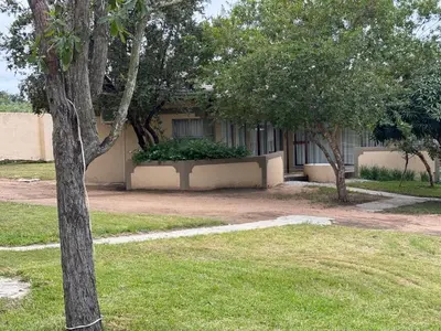 a building with trees in front of a yard at Soaring Summit Lodge in Ronaldsey