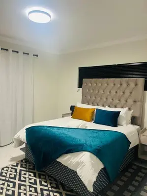 a bedroom with a large bed with blue and yellow pillows at KT Comfort in Midrand