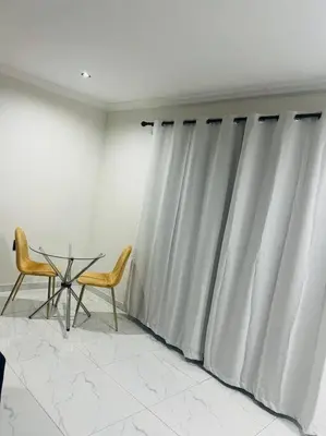 a room with a table and two chairs and curtains at KT Comfort in Midrand