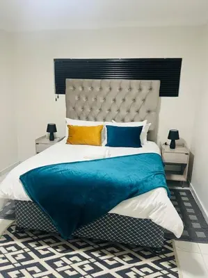 a bedroom with a large bed with a blue blanket at KT Comfort in Midrand