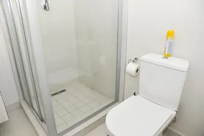 a white bathroom with a shower and a toilet at Eirini Elegant - Hermes Apartment in Midrand