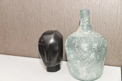 a green glass bottle and a black vase on a table at Eirini Elegant - Hermes Apartment in Midrand