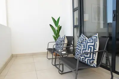 a row of chairs with blue and white pillows on them at Eirini Elegant - Hermes Apartment in Midrand