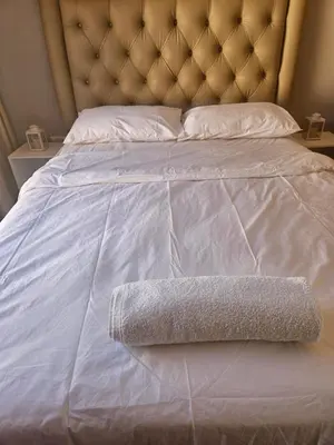 a white bed with a headboard and a towel on it at Feel at Home in Monavoni