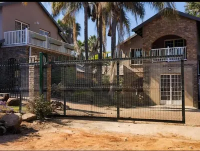 a fence in front of a house with palm trees at Melodie Guest House in Lone Star Texas