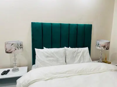 a bed with a green headboard and two lamps at Melodie Guest House in Lone Star Texas