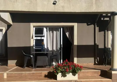 a patio with a table and chairs and flowers at The Zebra Suite at Frederick's Place in Pretoria