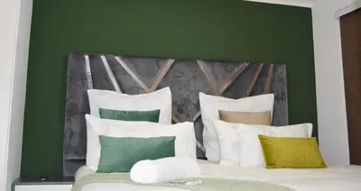 a green bedroom with a bed with white pillows at Moon Octave in Midrand