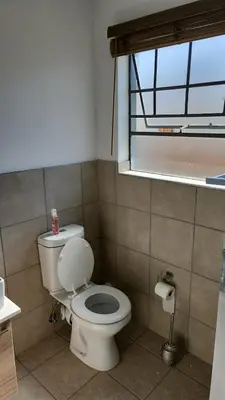 a bathroom with a white toilet and a window at Moon Octave in Midrand