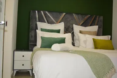 a bedroom with a large white bed with green walls at Moon Octave in Midrand