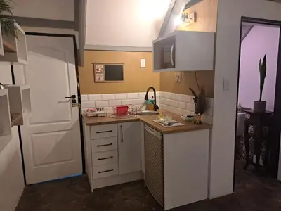 a small kitchen with a sink and a white door at Casa Mana Air B&B in Pretoria
