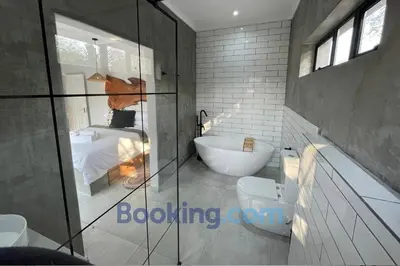 a bathroom with a tub and a sink and a bedroom at Shomoro Rest in Marloth Park