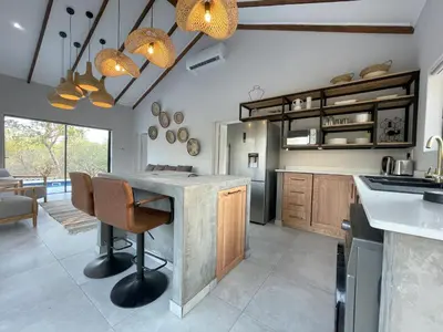 a kitchen with a counter and a table with chairs at Shomoro Rest in Marloth Park