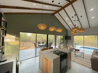 a kitchen and living room with a view of a pool at Shomoro Rest in Marloth Park