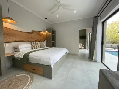 a bedroom with a large bed and a swimming pool at Shomoro Rest in Marloth Park