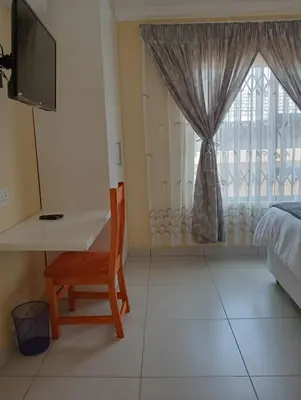 a bedroom with a desk and a bed and a window at SammyGrace Holiday Home in Tzaneen