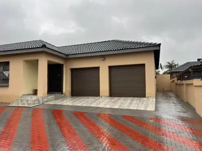 a house with two garage doors on a driveway at SammyGrace Holiday Home in Tzaneen