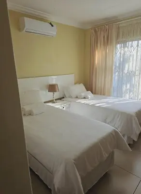 two beds in a hotel room with a window at SammyGrace Holiday Home in Tzaneen
