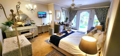 a bedroom with a bed and a desk and a mirror at Harmony Suite in Pretoria