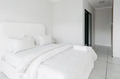 a white bed with white sheets and pillows on it at The Blyde Crystal Villa Apartment in Pretoria