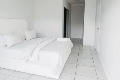 a white bed with white sheets and pillows on it at The Blyde Crystal Villa Apartment in Pretoria
