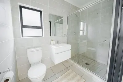 a white bathroom with a toilet and a shower at The Blyde Crystal Villa Apartment in Pretoria